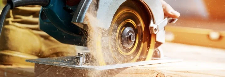 Hand schneidet Holz mit Kreissäge